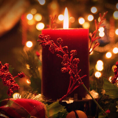 Eine brennende rote Kerze vor adventlichem Hintergrund