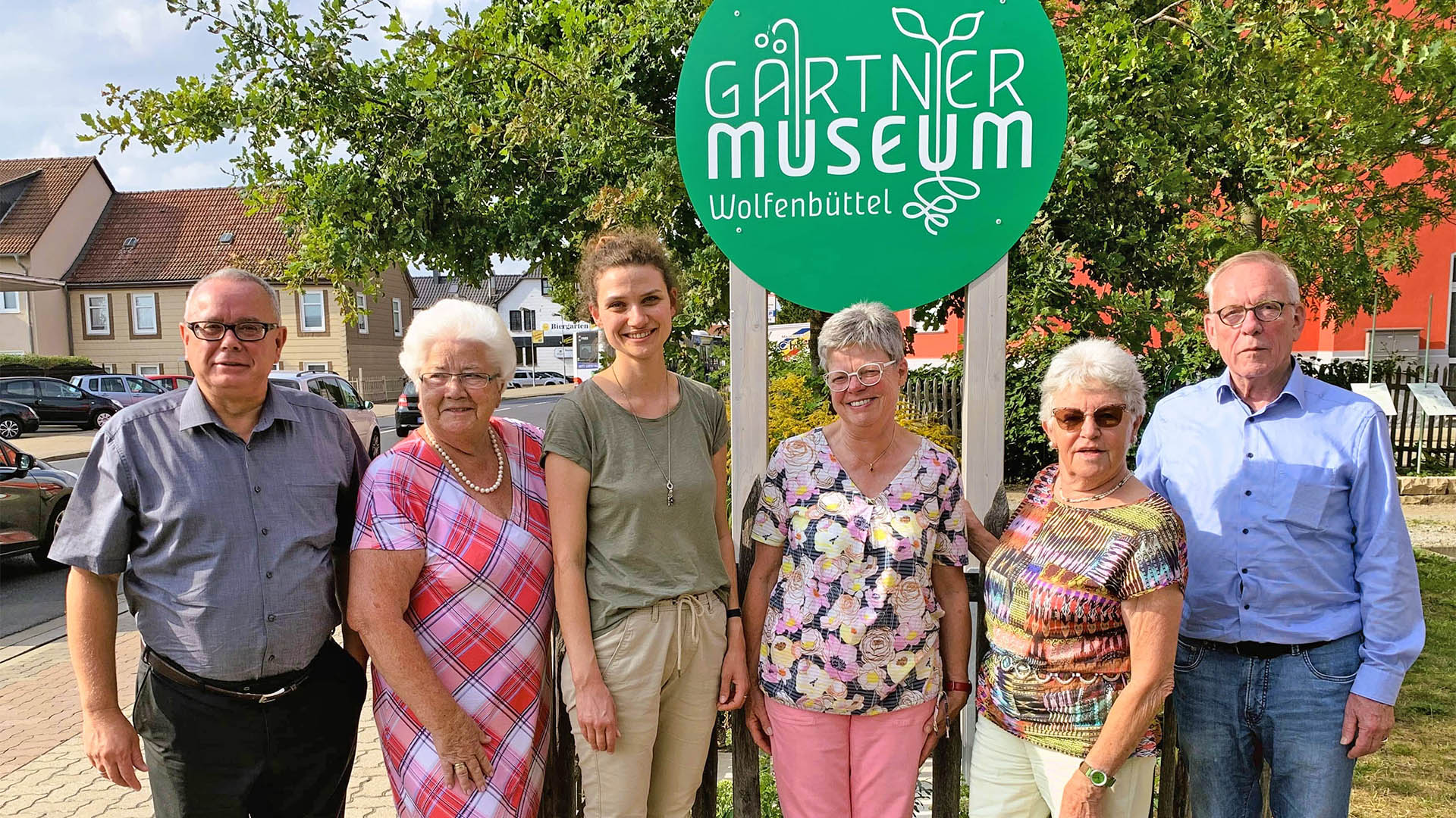 Zwei Männer und vier Frauen stehen vor dem Schild des Gärtnermuseums