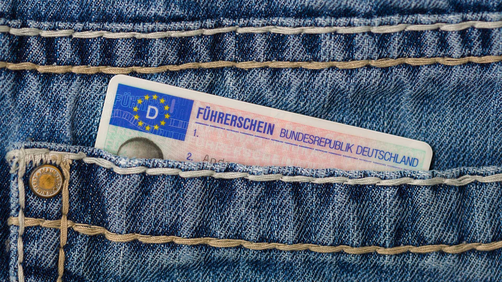 Ein Führerschein steckt zum Teil aus einer Jeans-Hosentasche.
