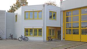 Ein grau-gelbes Gebäude mit einer Einfahrt für den Hubschrauber..