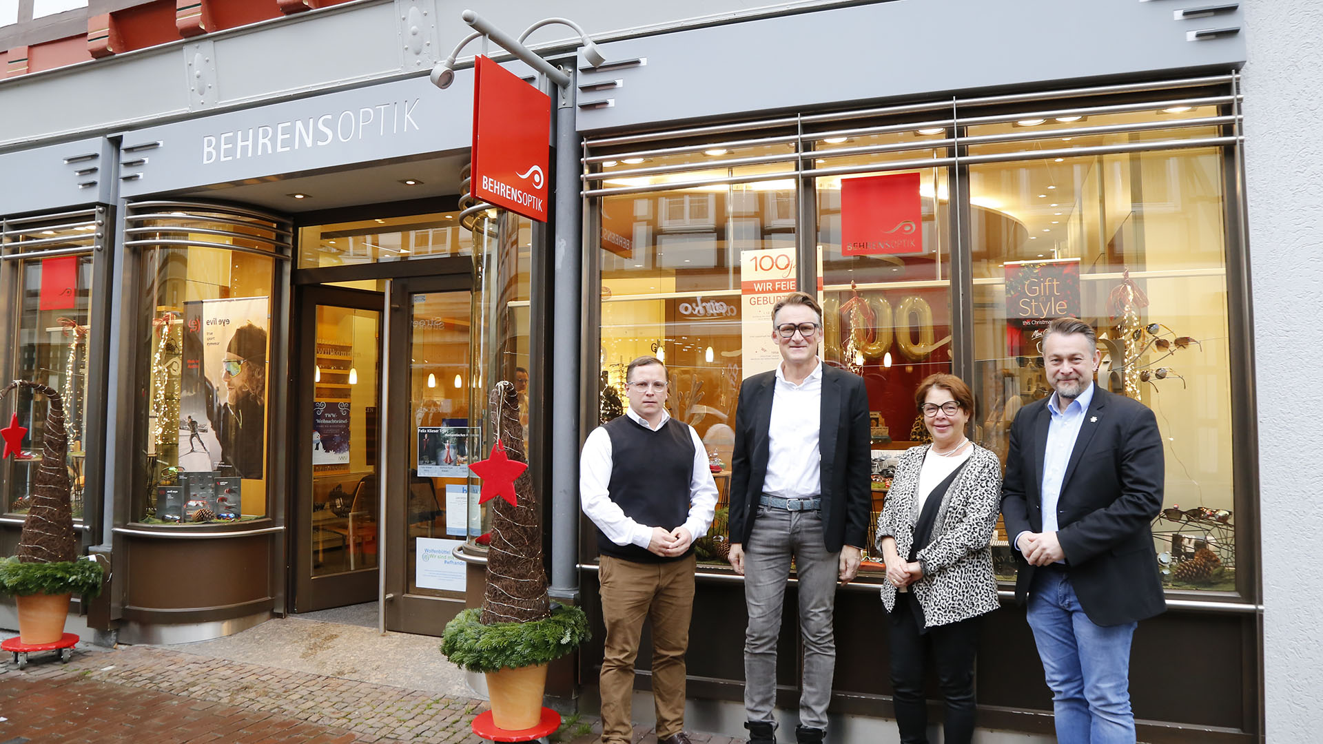 Drei Männer und eine Frau stehen zum Gruppenfoto vor dem Ladenlokal von Behrens-Optik