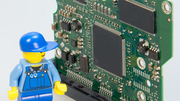 Eine Lego-Figur in Form eines Elektrikers steht neben einer Platine.
