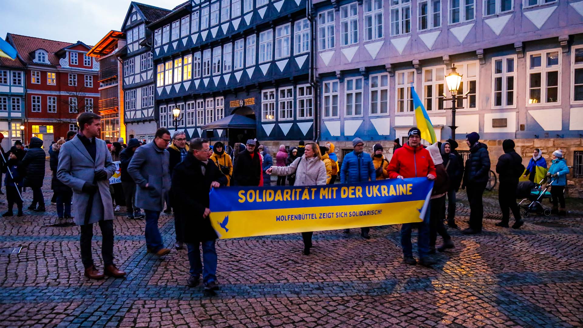 Viele Personen mit Bannern und ukrainischen Flaggen auf dem Stadtmarkt. Dabei ein großes Banner in blau-gelb mit der Aufschrift "Solidarität mit der Ukraine".