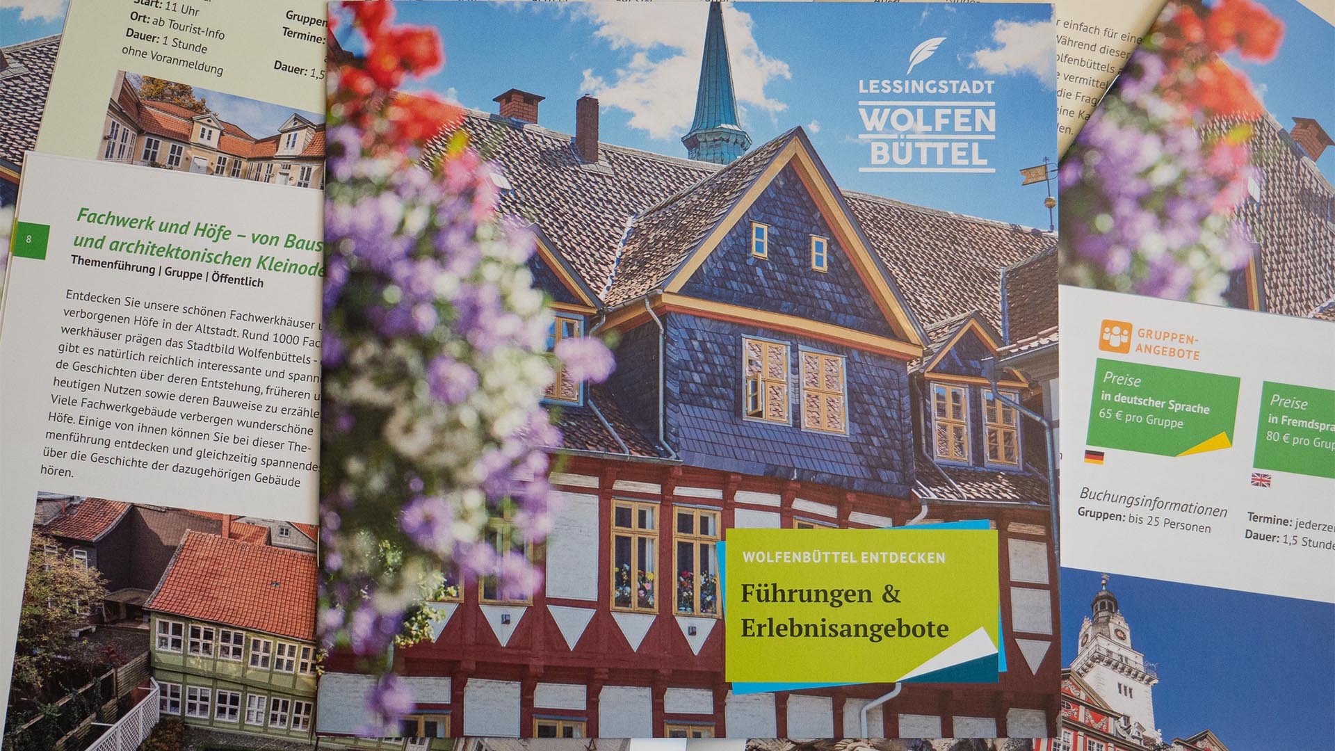 Die Broschüre "Wolfenbüttel entdecken" liegt auf einigen aufgeschlagenen Exemplaren, sodass man sowohl das Titelbild als uch einige Ausschnitte der Innenseiten erkennen kann.
