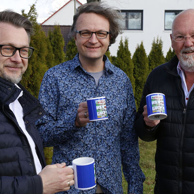 Bürgermeister Ivica Lukanic, Zeichner Tobi Wagner und der Wendesser Ortsbürgermeister Andreas Rink halten "Willkommen in Wendessen-Kaffeetassen in den Händen.