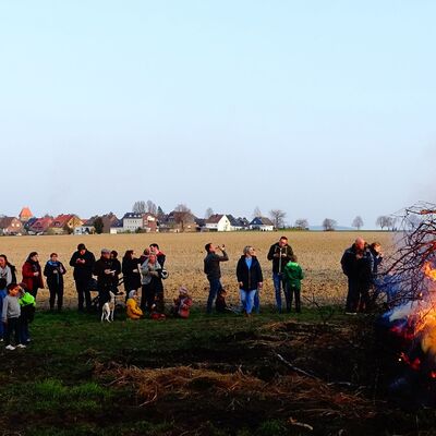 Mehrere Personen stehen vor einem Osterfeuer.