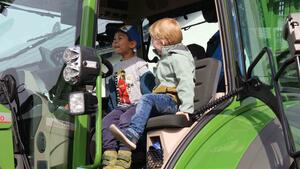 In der Fahrerkabine eines Traktors sitzen zwei Jungs auf dem Fahrer- und Beifahrersitz.