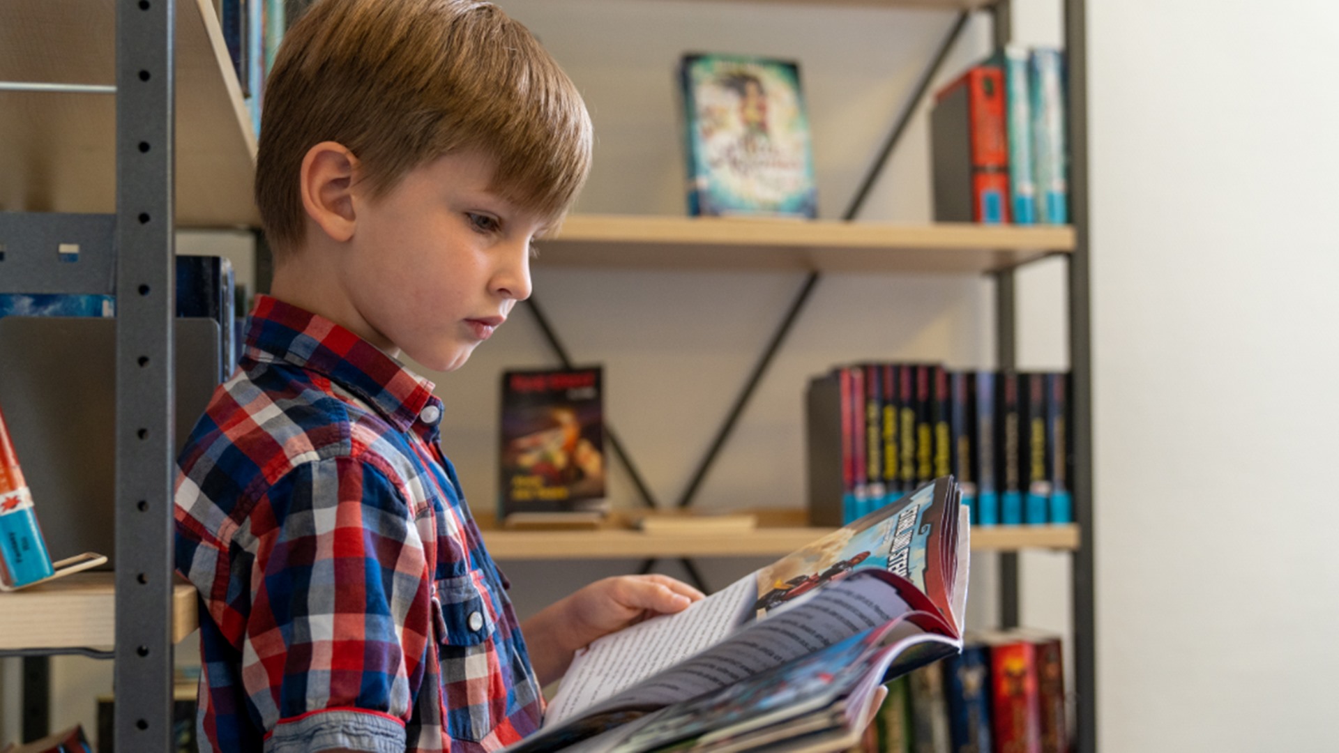 Ein Junge liest in der Stadtbücherei in einem Buch.