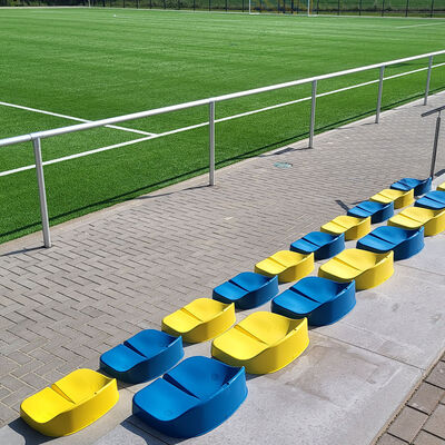 Gelbe und blaue Sitze neben einem Fußballplatz.