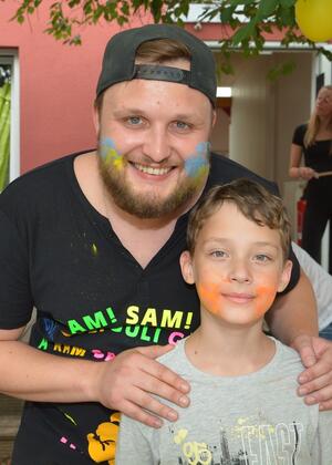 Porträt eines jungen Mannes mit einem Jungen. Der Mann hat die Farben der Ukraine, blau und gelb, als Streifen auf den Wangen.