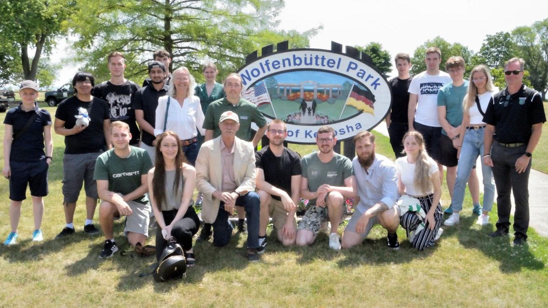 Rund 20 Männer und Frauen stehen und hocken zum Gruppenfoto neben einem Schild "Wolfenbüttel Park".