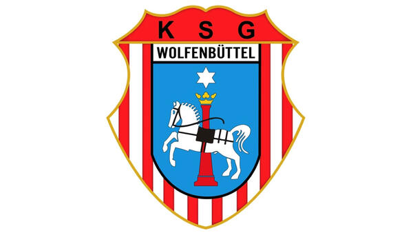 Wappen in Schildform, rot und weiß längsgestreift. In der Mitte steht das Wolfenbütteler Stadtwappen, darüber die Buchstaben KSG.
