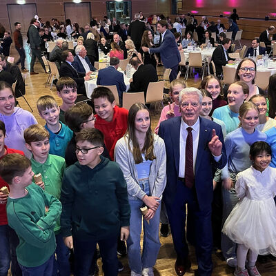 Viele Jugendliche umringen in einem Saal um Bundespräsident a. D. Joachim Gauck für ein Foto