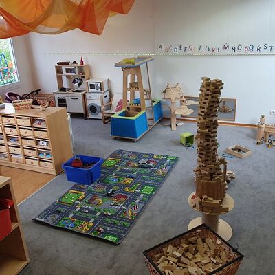 Blick in einen Kita-Raum mit Spielzeug, einem Teppich mit Straßen, Holzspielszeut