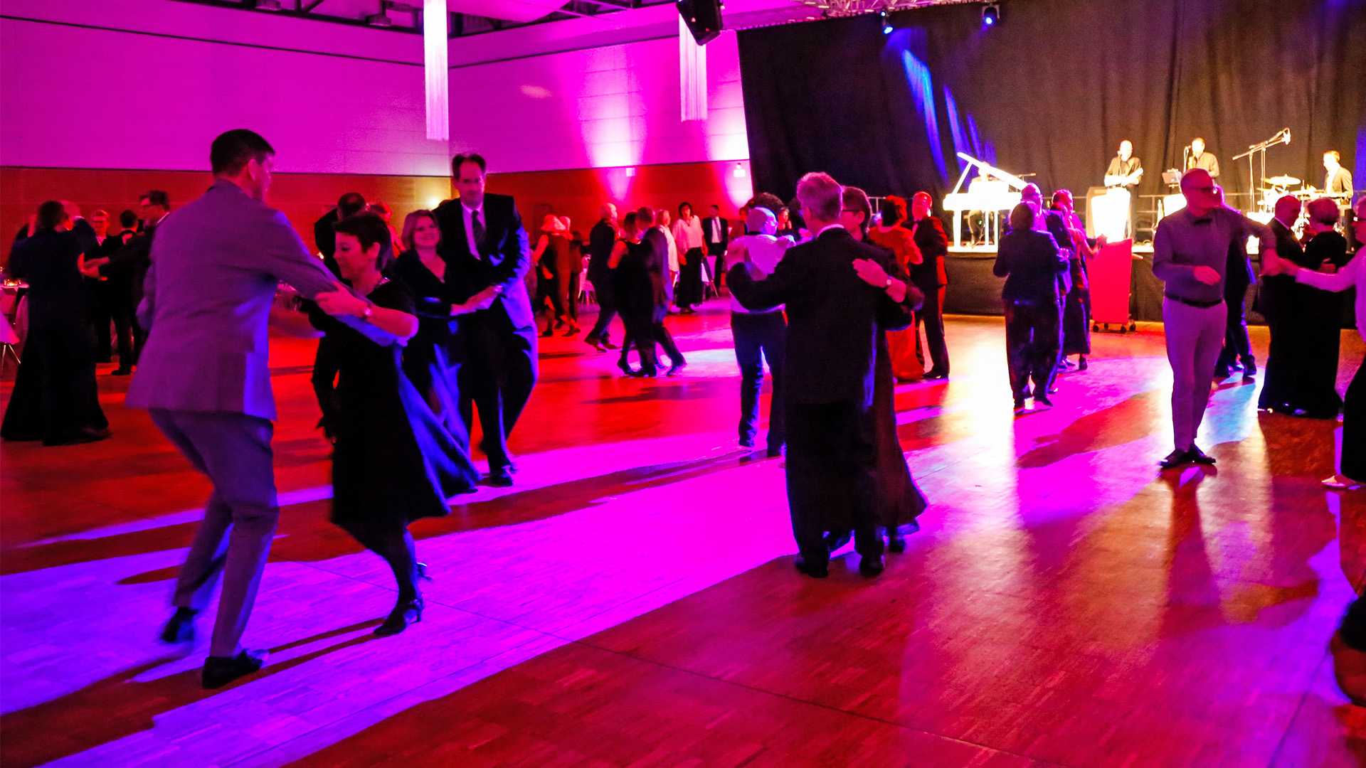 Tanzpaare auf einer violett beleuchteten Tanzfläche