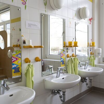 Kita-Badezimmer mit Waschbecken, Zahnputzbechern, Handtüchern