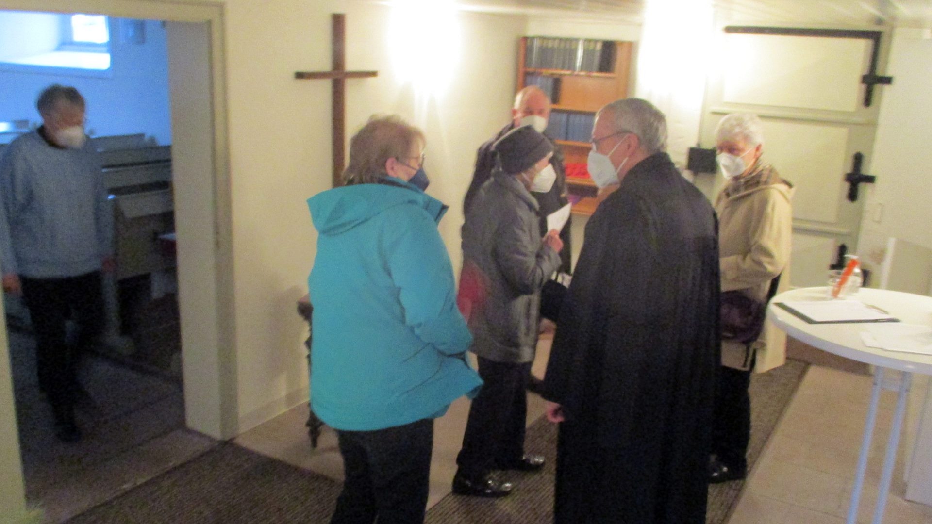 Mehrere Besucher stehen im Vorraum der Kirche und reden miteinander. Alle tragen einen Mund-Nase-Schutz.