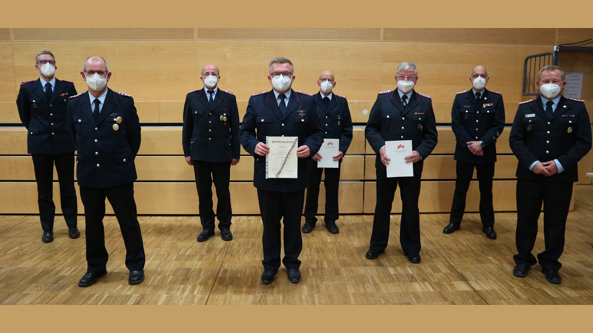 Acht Feuerwehrmänner in Uniform, zum Teil halten sie Urkunden in den Händen